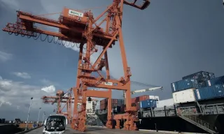 Ship-to-shore cranes over stacked containers at a port terminal.